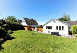 A residential property with a well-maintained lawn, a small patio area, and a white building with a sloped roof.