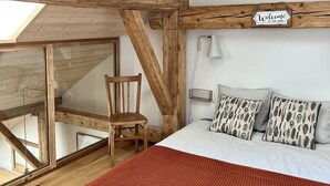 A bedroom with a sloped ceiling, a skylight, a wooden chair, a bed with patterned pillows, and a 'Welcome to our home' sign. - Triplex In The Heart Of Chamonix (Chamonix-Mont-Blanc)