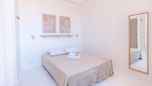 Een slaapkamer met een bed, een spiegel en twee kunstwerken aan de muur.