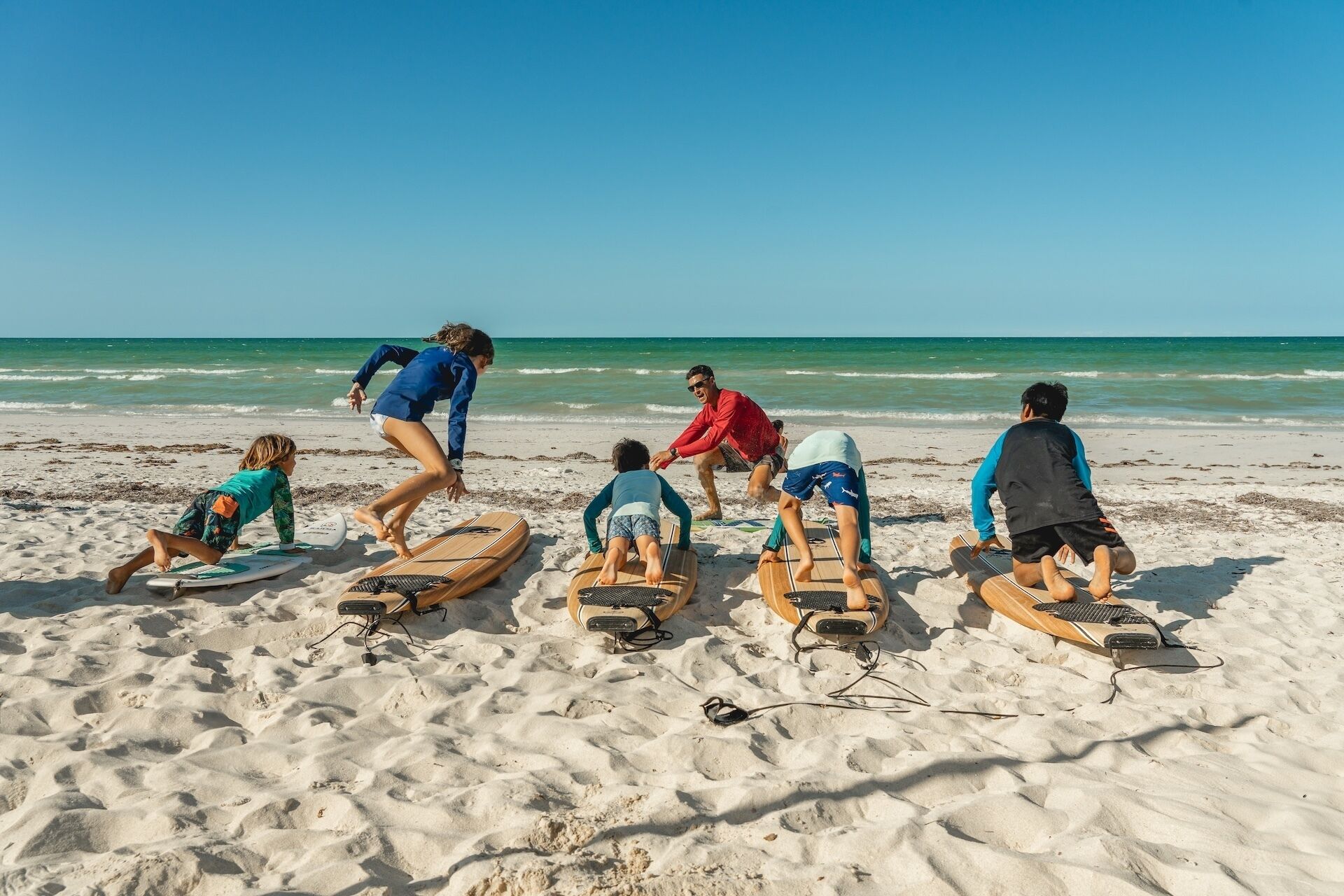 Eine Szene am Strand mit Menschen auf Surfbrettern.