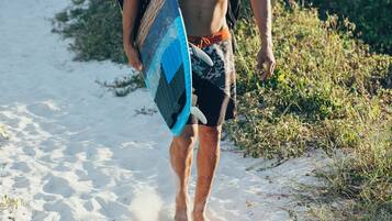 A person walking on a sandy path with a surfboard.