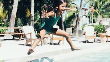 Guests can enjoy a refreshing swim in the pool surrounded by palm trees and lounge chairs.