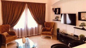 Una sala de estar con sofá, sillones, televisor y mesa de centro.