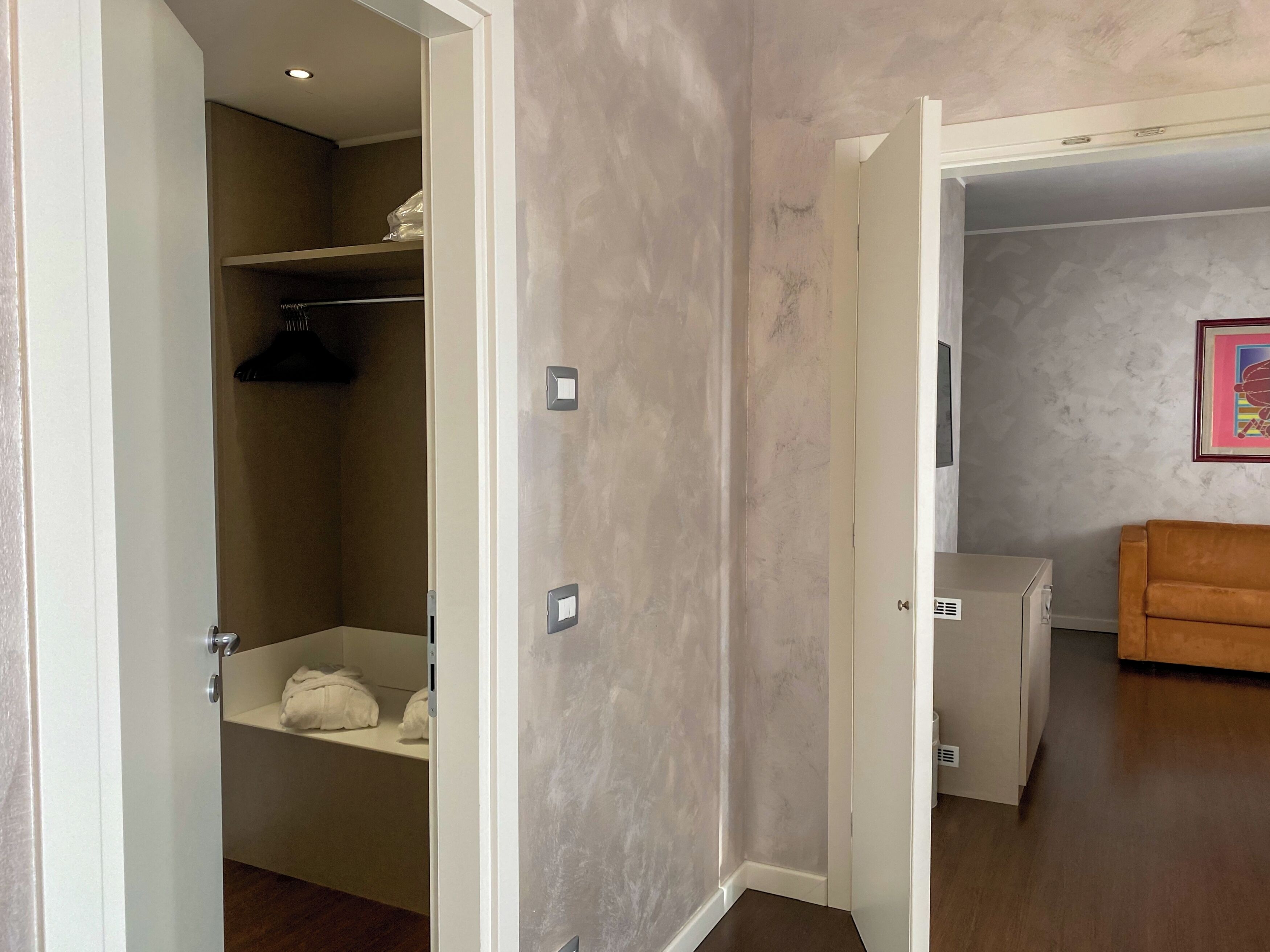 Een kamer met een badkamer, een wit kastje en een bruine bank.