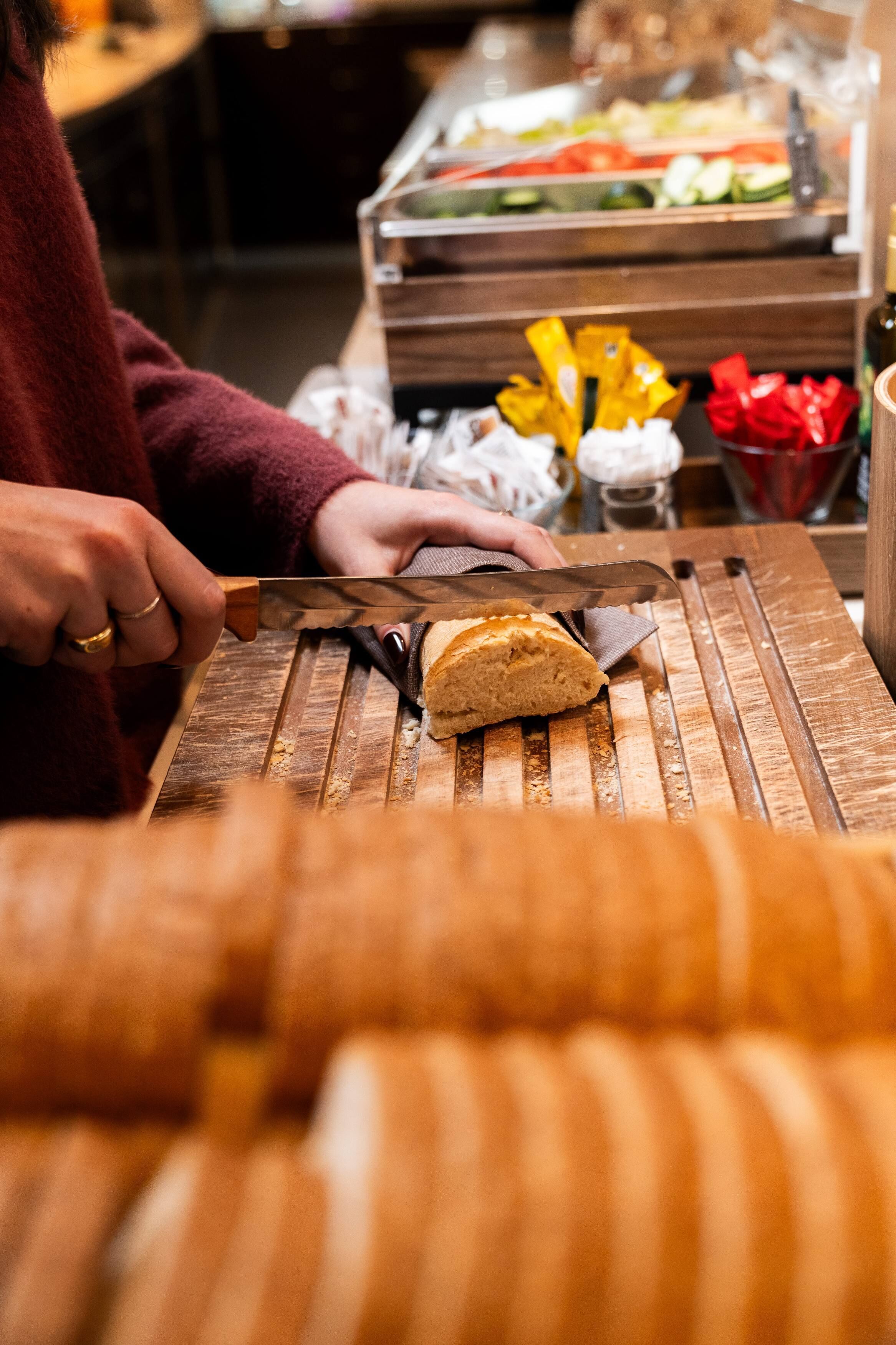 Una persona cortando pan sobre una tabla de madera.