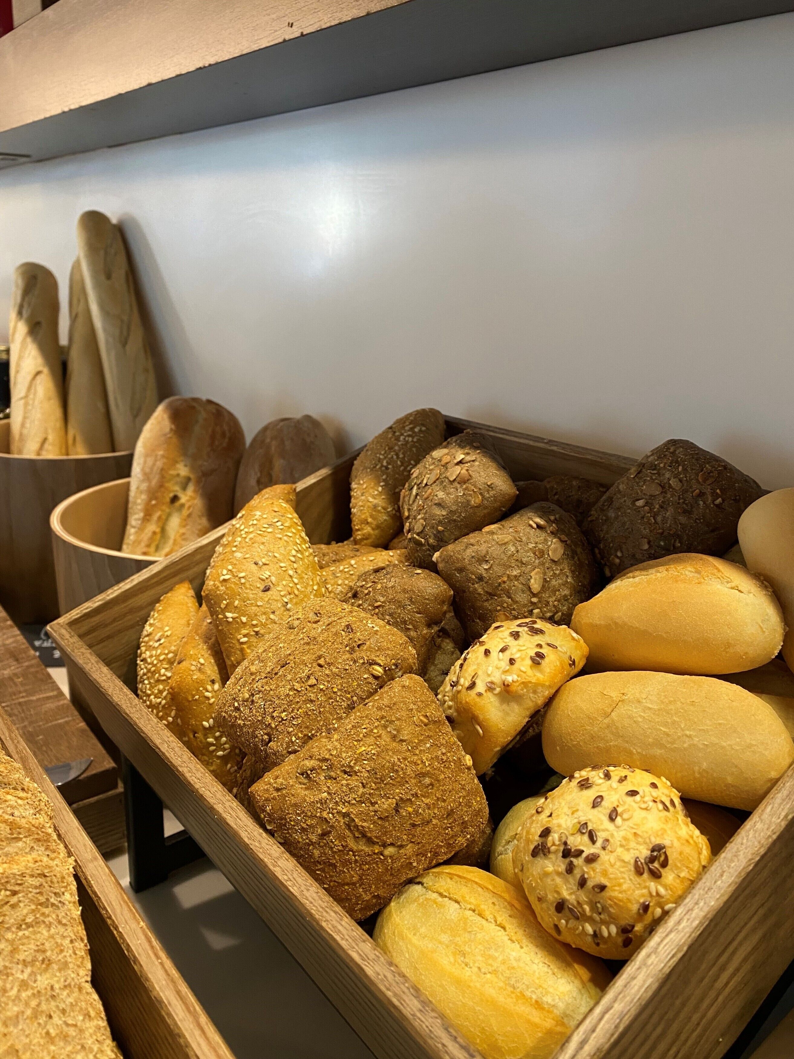 Un expositor de madera lleno de diferentes tipos de pan.