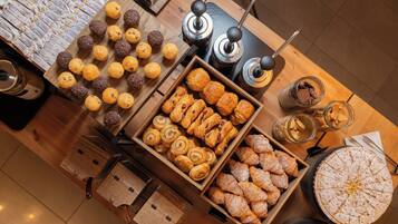Une variété de pâtisseries et de produits de boulangerie sont exposés sur une table en bois.