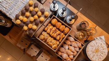 Verschiedene Backwaren, darunter Muffins, Croissants und Gebäck, stehen auf einem Holztisch.