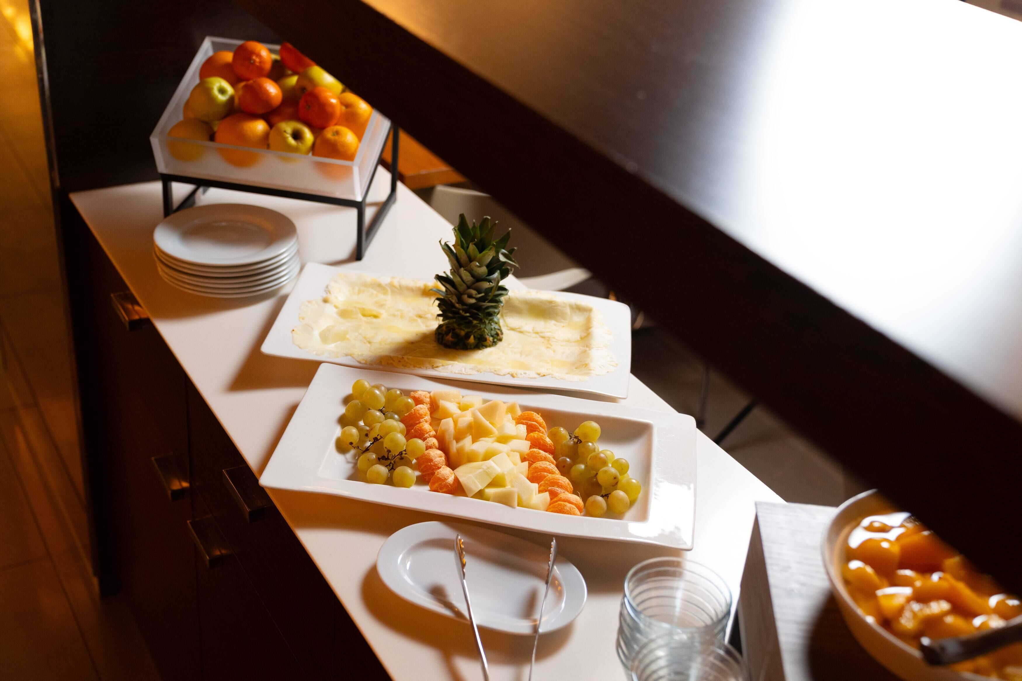 A buffet table with various fruits and cheeses.