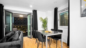 Ein modernes Wohnzimmer mit einem Glastisch, schwarzen Stühlen, einem schwarzen Sofa und einer Topfpflanze.