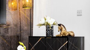 Ein schwarzer Konsolentisch mit einer Vase weißer Blumen und einer goldenen Statue.