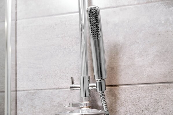 A chrome showerhead with a flexible hose attached to a wall-mounted fixture.