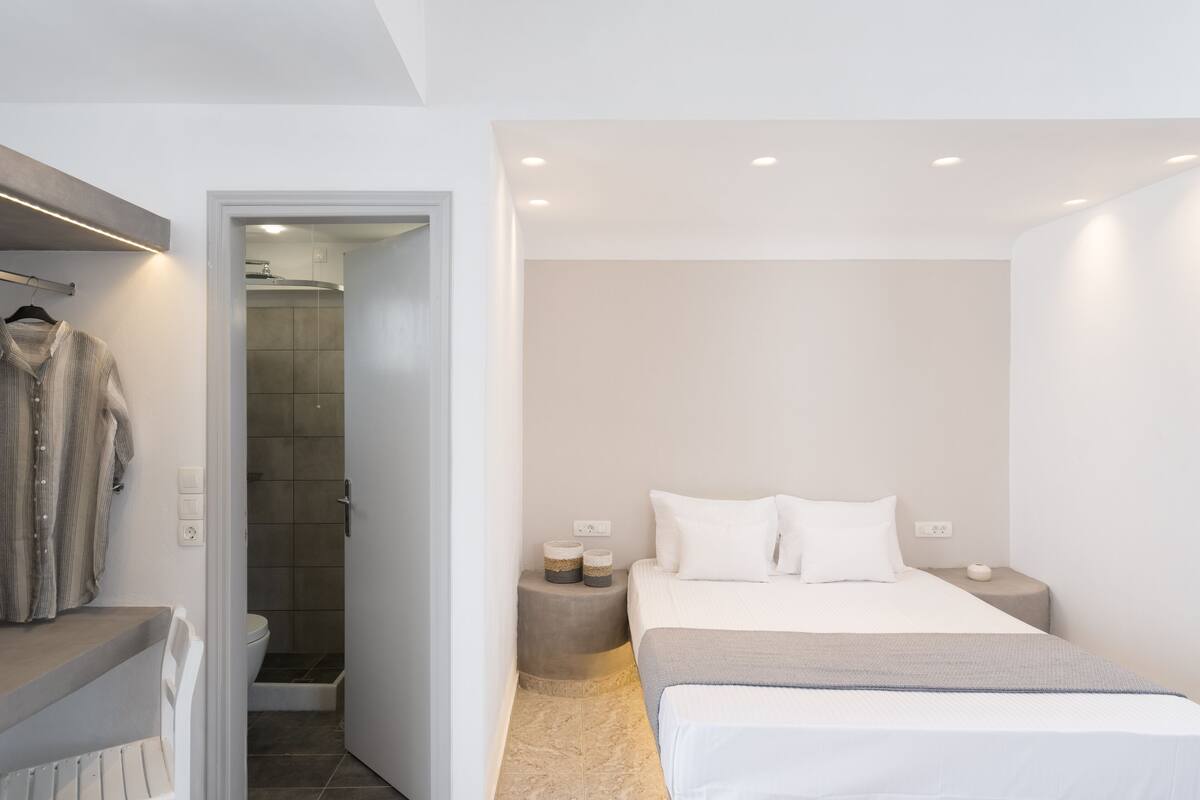 Une chambre à coucher moderne avec un lit, des tables de chevet et un espace douche.