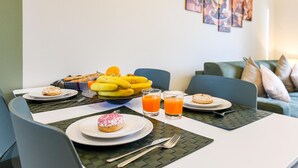 A breakfast setup with plates of food, a bowl of fruit, and glasses of orange juice on a table. - Appartamento Ulivo in Sal (Salò)
