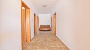 Un pasillo con puertas de madera, un banco y una lámpara en el techo.