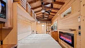 Een houten blokhut met een groot bed, een open haard en een televisie.