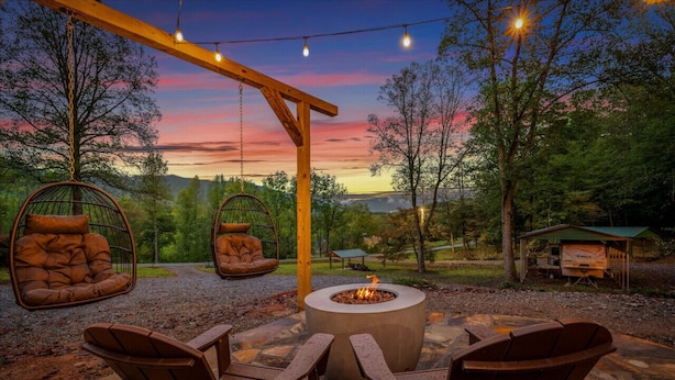 Een terras met buitenmeubilair, een vuurkorf en een pergola met lichtjes.
