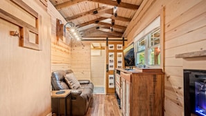 Een knus interieur van een blokhut met houten details, een open haard, een zithoek met een leren bank en een kleine tafel.