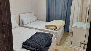 Ett hotellrum med två sängar, ett litet skrivbord och en spegel.