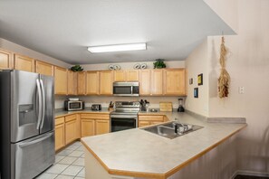 A modern kitchen with stainless steel appliances, wooden cabinets, and a large island with a sink.