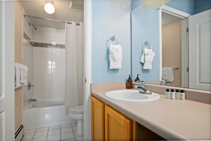A bathroom with a bathtub, toilet, sink, and a mirror.