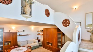 A spacious living area with a dining table, sofa, and a staircase with decorative wall panels. - The Window to the sky (Amalfi)