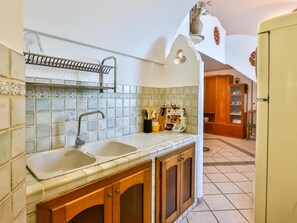 Una cocina con dos fregaderos, armarios de madera, un perchero y salpicadero de azulejos.