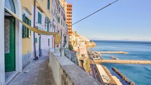 A narrow street with buildings on one side and a waterfront on the other. - The Window to the sky (Amalfi)