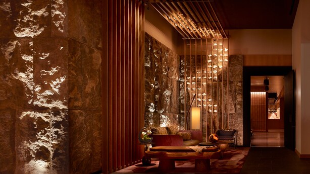 A modern interior with a stone wall, wooden slats, and a seating area with a sofa and armchairs. - Nobu Hotel Atlanta (Atlanta)