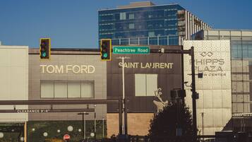 A building with signage for Tom Ford and Saint Laurent, a stop sign, and a traffic light at Peachtree Road intersection.