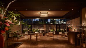 A modern indoor space with a high ceiling, large windows, and a view of the cityscape. There are several tables and chairs arranged for dining or socializing. - Nobu Hotel Atlanta (Atlanta)