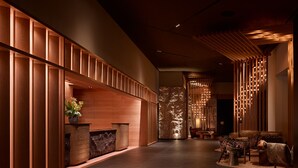 A modern lobby with wooden paneling, a reception desk, seating area, and a decorative wall with hanging lights. - Nobu Hotel Atlanta (Atlanta)