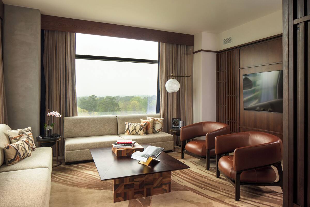 A modern living room with a sofa, two armchairs, a coffee table, and a television.