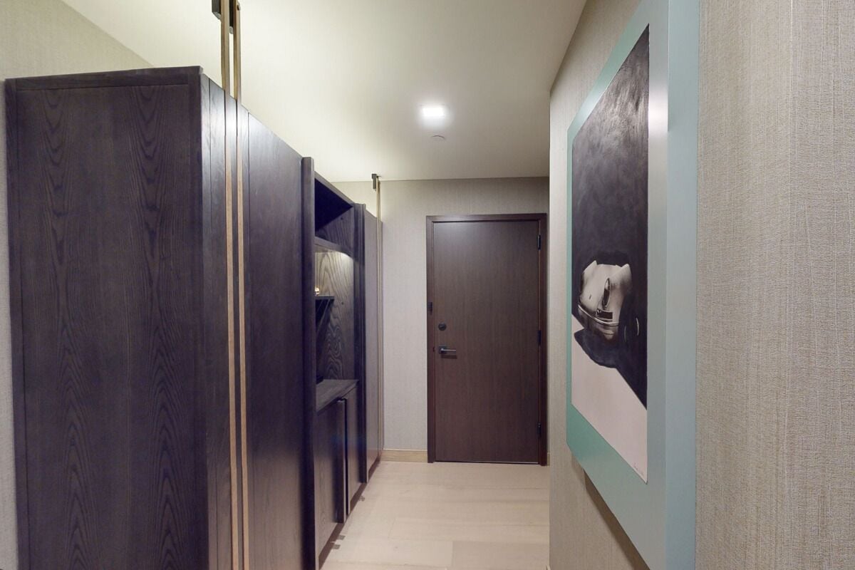 Un pasillo con un armario de madera oscura, una puerta y un cuadro en la pared.