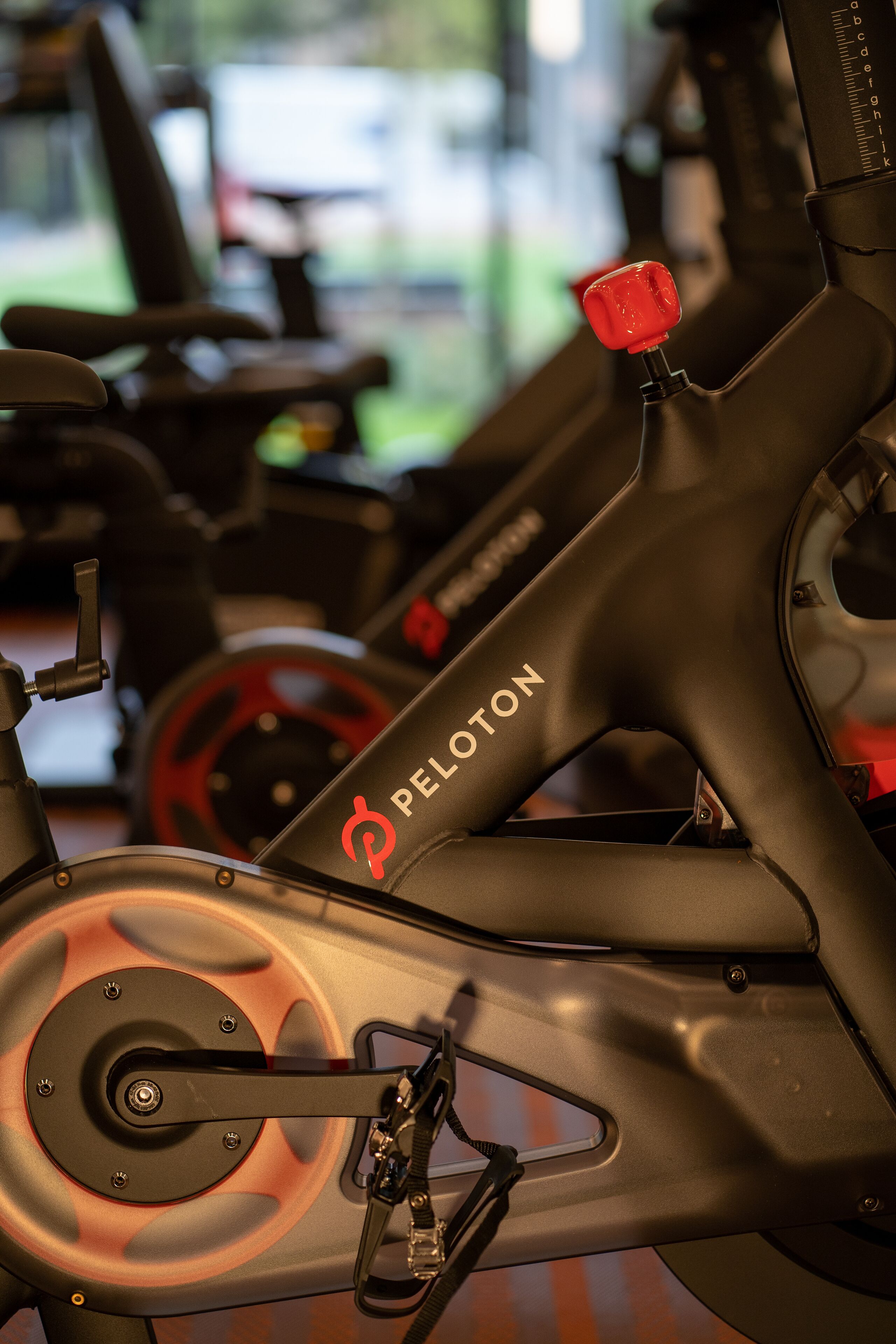A Peloton stationary bike with a red knob, a digital display, and a branded logo.