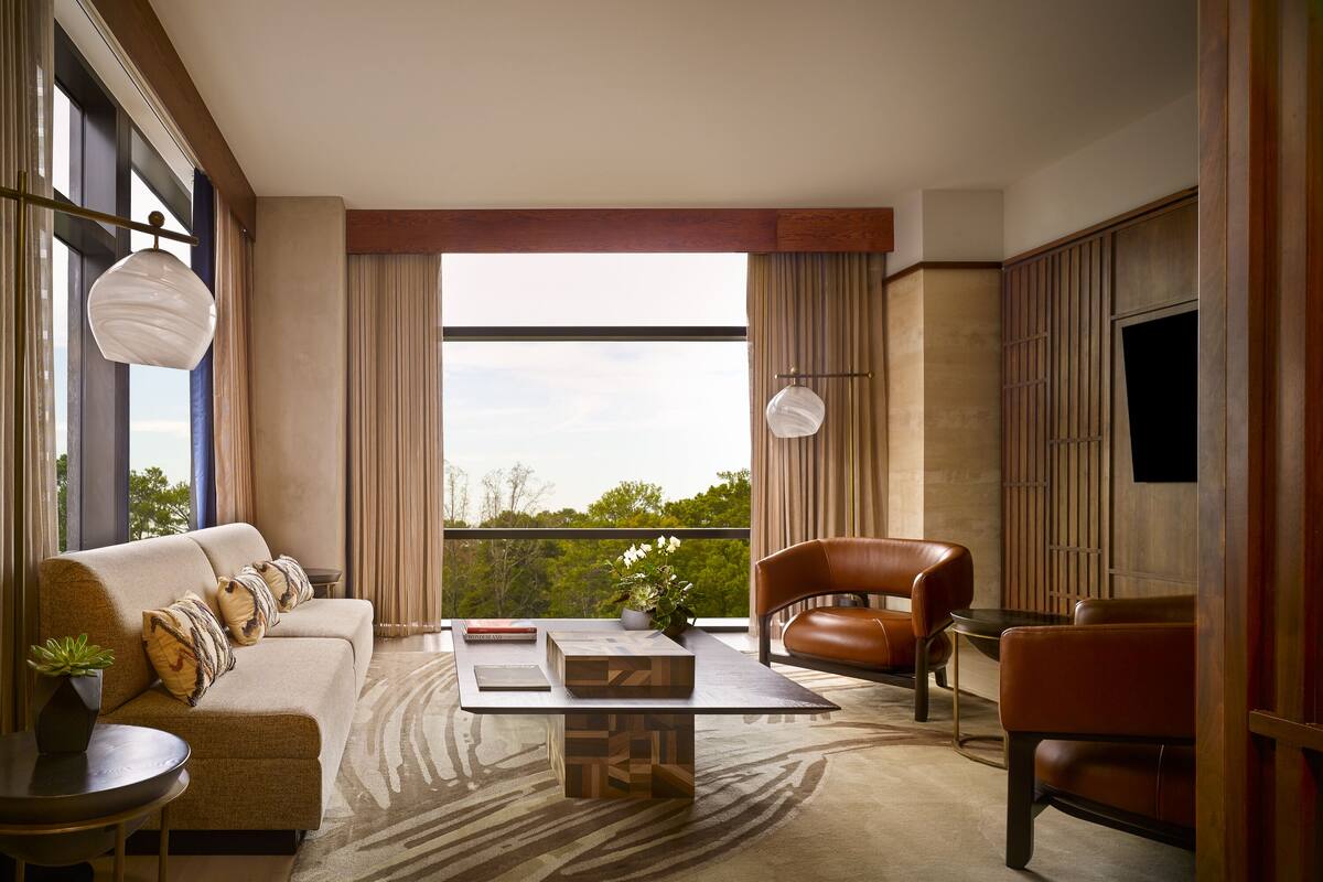 A modern living room with a sofa, armchair, coffee table, and a view of the outdoors.