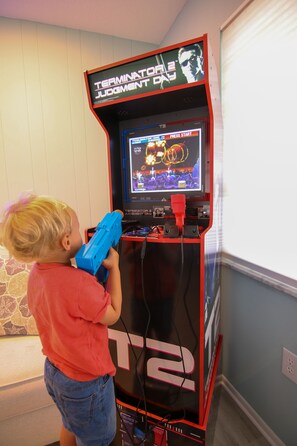 Un niño jugando un videojuego en una máquina arcade roja con una pantalla que muestra el juego 'Terminator Judgment Day'.