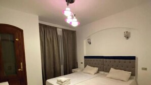 Una camera d'albergo con un letto grande, una porta in legno e una lampada a soffitto.