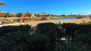 Un resort con piscina, area spiaggia e costruzioni a tetto di paglia.