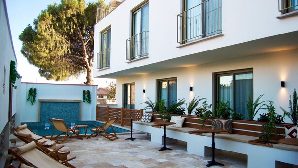 A modern outdoor patio with lounge chairs, a pool, and potted plants. - Boja Küçükköy (Ayvalik)