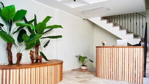 A reception area with a wooden reception desk, potted plants, and a staircase leading to an upper floor. - Boja Küçükköy (Ayvalik)