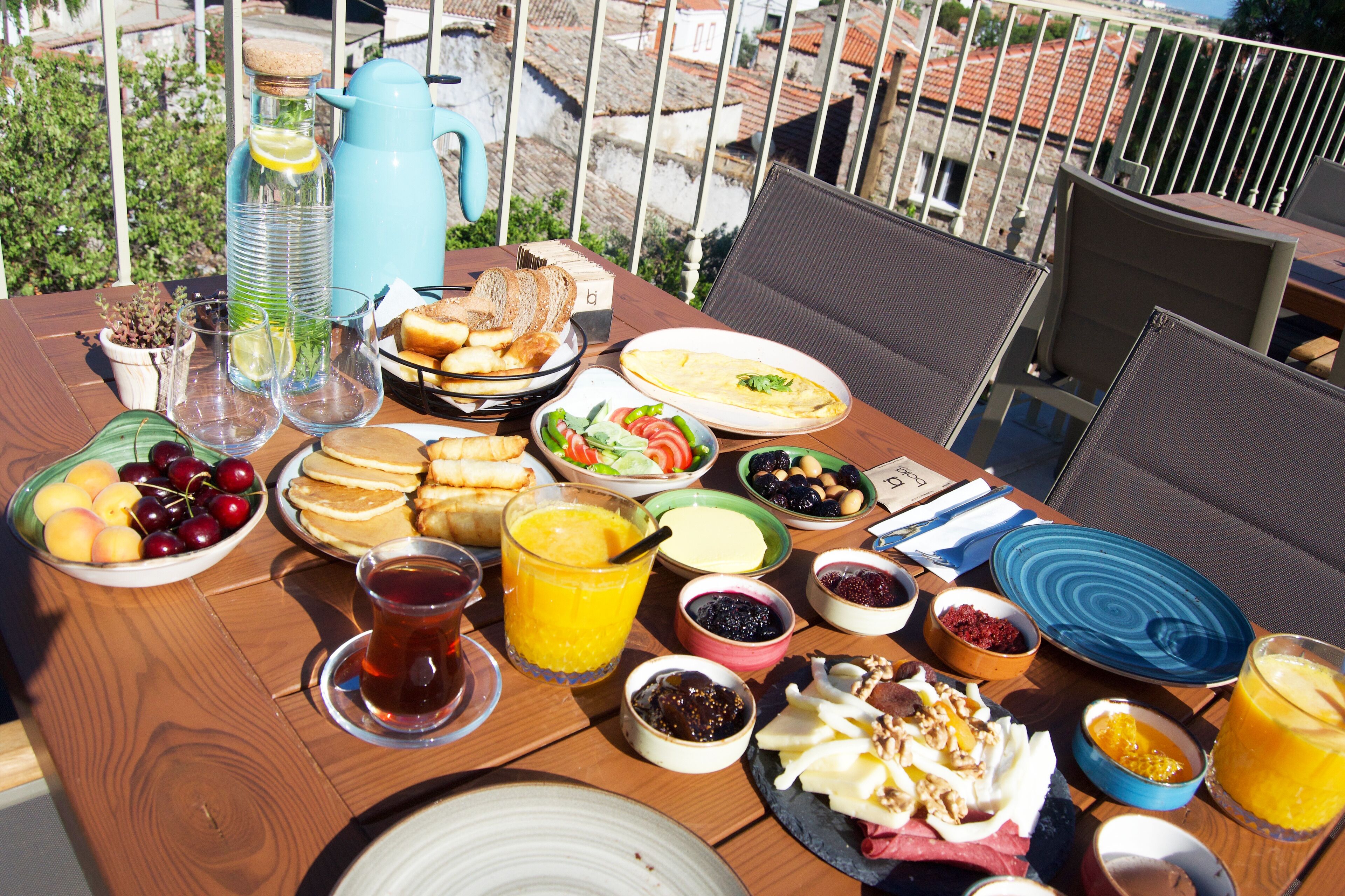 A breakfast table with various food items and drinks, including fruits, bread, and a pitcher.