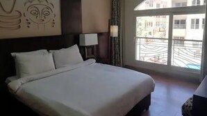 A hotel room with a large bed, a wall-mounted artwork, a window with a view of the outside, and a balcony. - 2 bedroom & breakfast in The Bosque Hotel Hurghada (Red Sea Governorate)