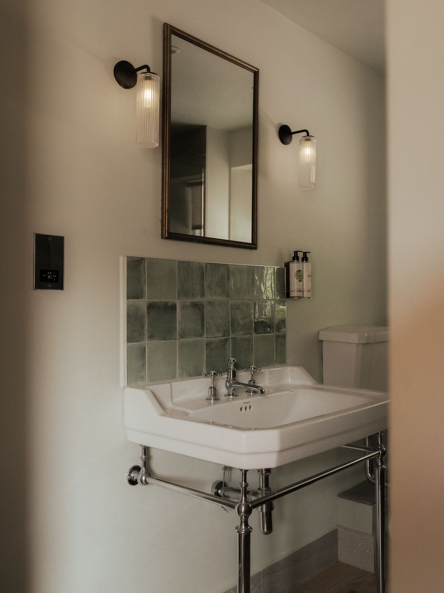 A bathroom with a white sink, a mirror, and two wall-mounted lights.