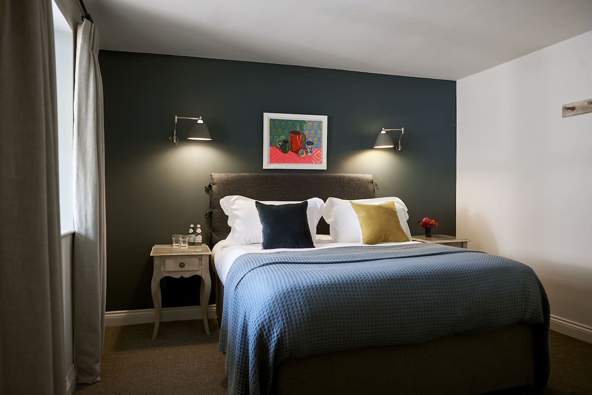 A neatly arranged hotel room with a bed, bedside tables, and a wall-mounted artwork.
