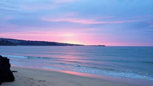 A beach with calm waters and a sunset.