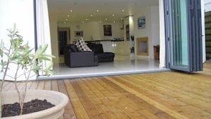 A modern living room with a sofa and a dining area visible through an open sliding door.