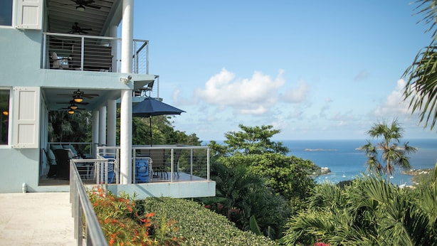 A two-story building with a balcony, a ceiling fan, and a view of the ocean. - Big Sky Villa: sunset view; great for large families; pool; back up power  (St. John USVI)
