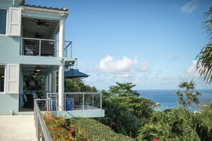 Ein zweistöckiges Gebäude mit Balkon, Deckenventilator und Meerblick.