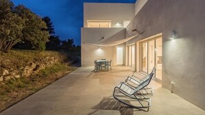Ein modernes Haus mit Terrasse, Essbereich und einer Sitzecke mit Stühlen.